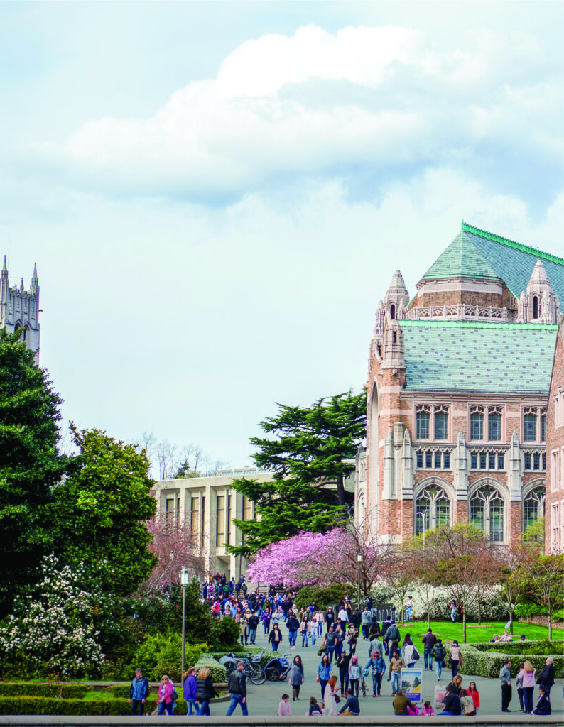 Photo of students walking on paved path on the UW campus with a shot of a brick building and trees